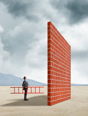 Fotos do Empresário, segurando a escada olhando para cima do muro alto Royalty Free